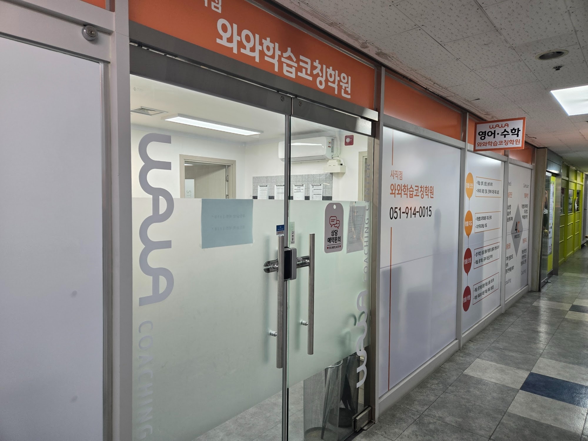 와와학습코칭 사직점 입구 — 상가 복도에 있는 주황색 간판과 유리문, 창에 붙은 사직점 안내와 맞춤 진단·맞춤 지도·맞춤 코칭·맞춤 처방 4C 프로세스 안내