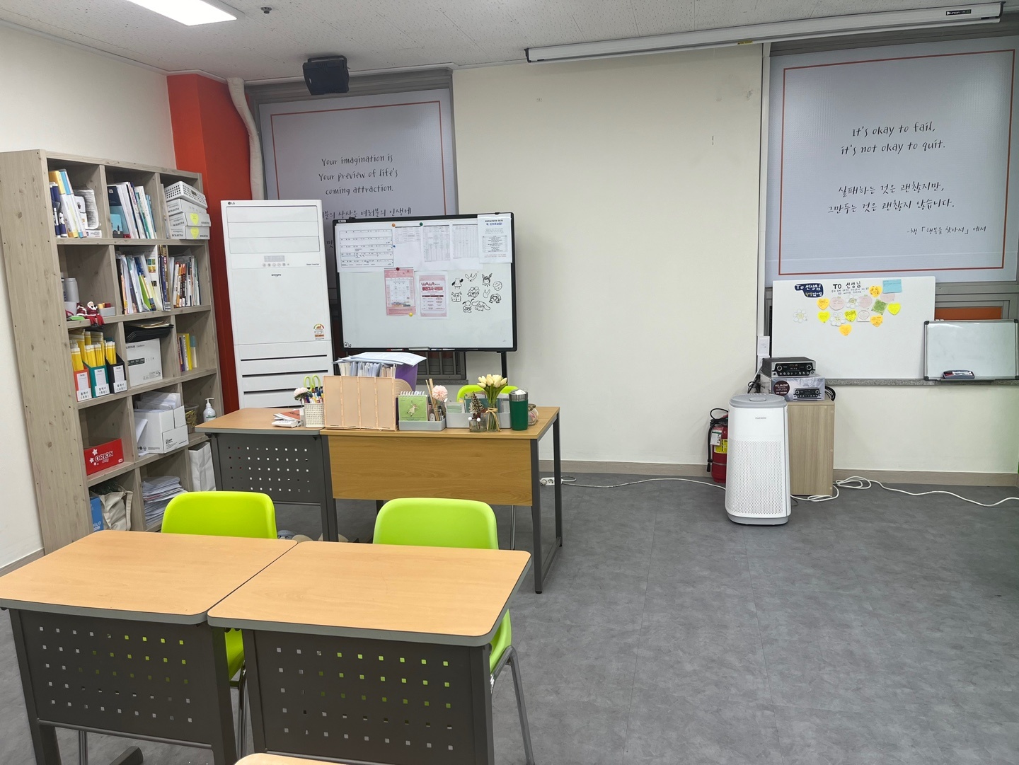 첨단점 교실 — 창문 블라인드에 적힌 'It's okay to fail, it's not okay to quit. 실패하는 것은 괜찮지만, 그만두는 것은 괜찮지 않습니다' 문구, 계획표가 붙은 이동식 화이트보드와 코치 책상
